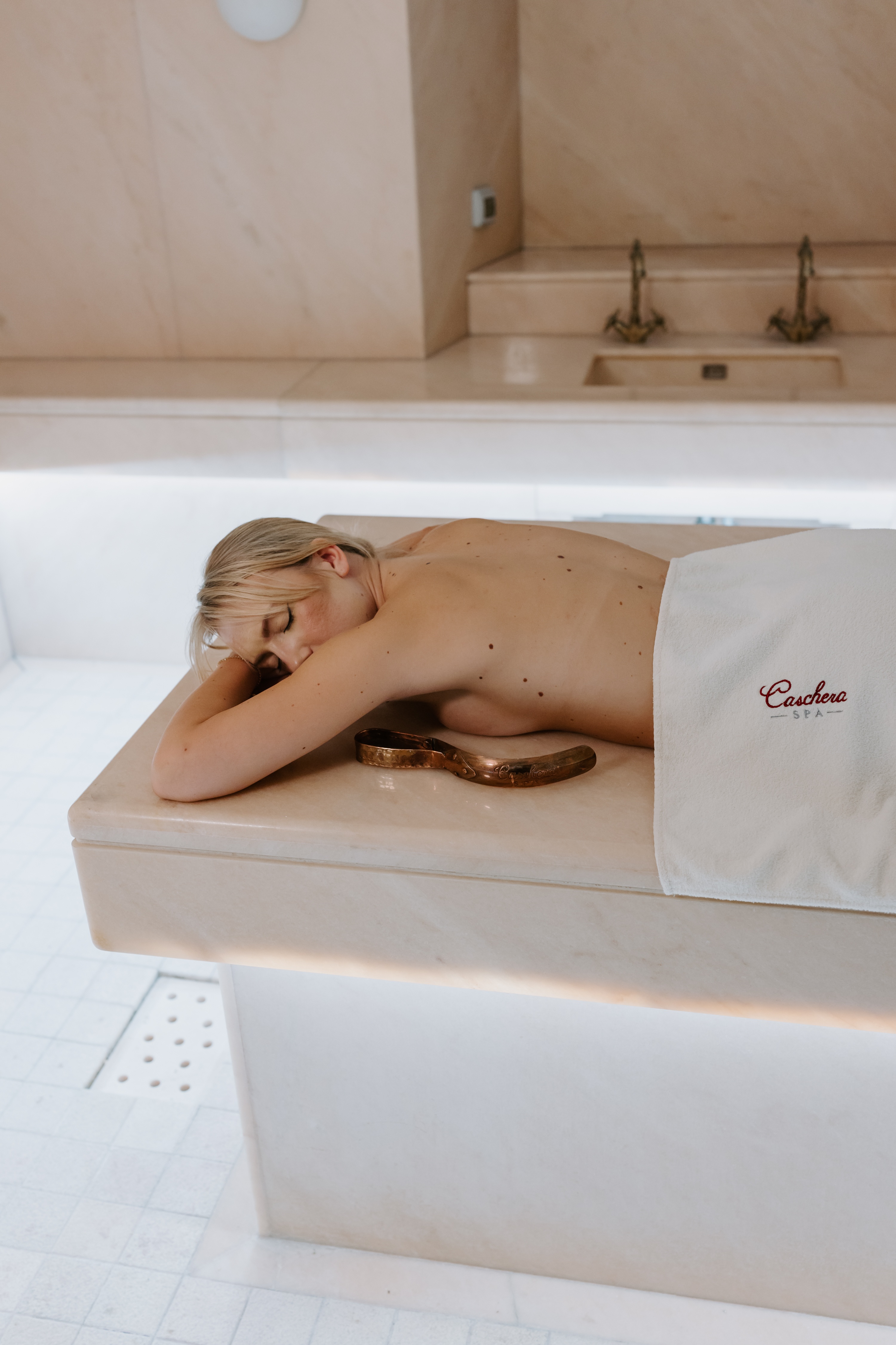 Donna sdraiata su lettino massaggio con pietre calde sulla schiena