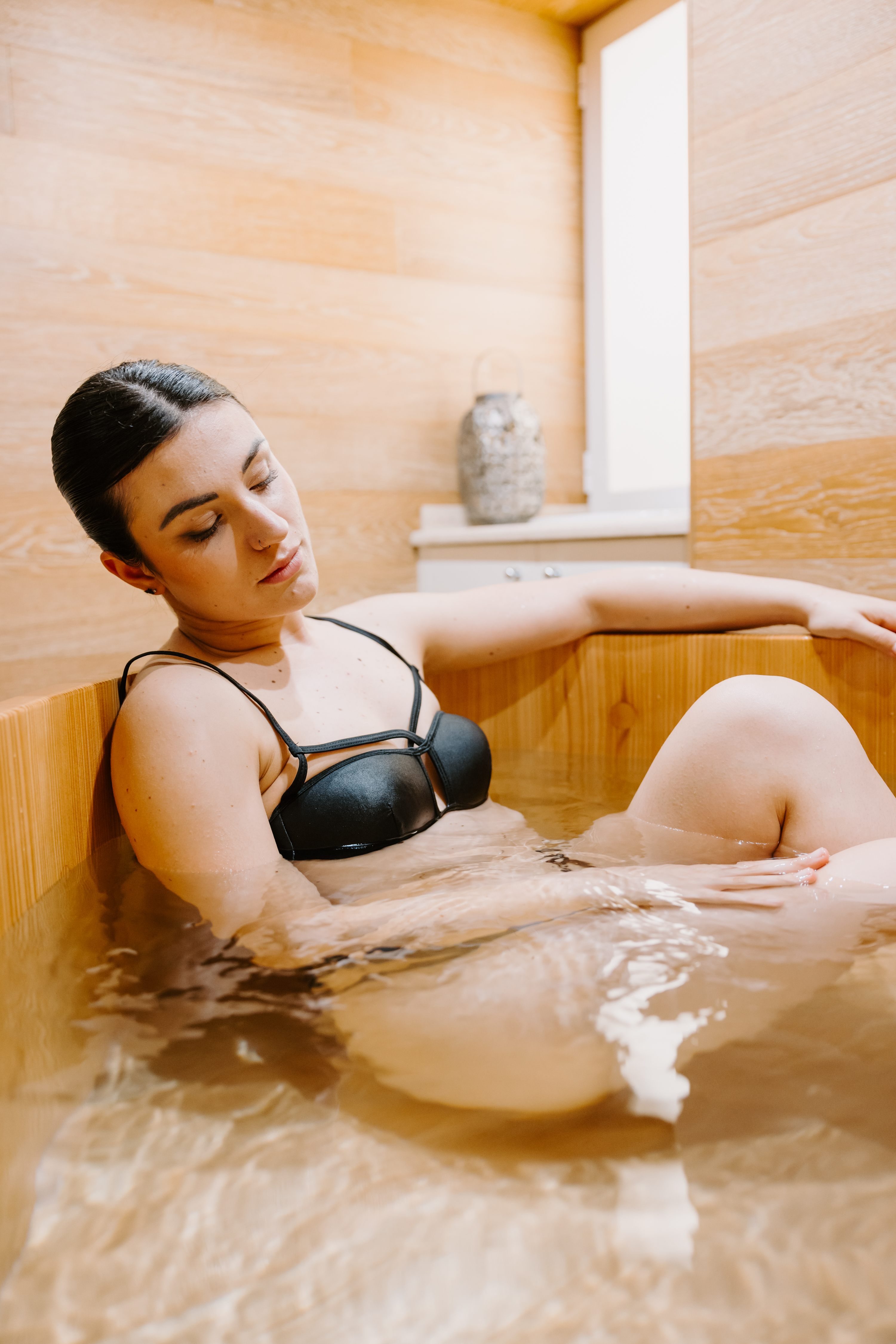 Donna che si rilassa in vasca di legno con illuminazione calda